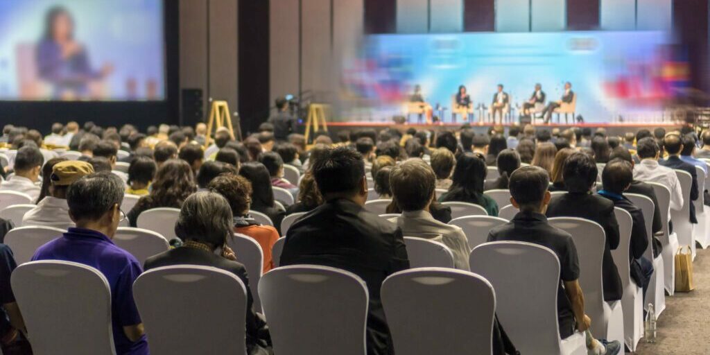 Rear view of Audience listening Speakers on the stage in the conference hall or seminar meeting, business and education about investment concept