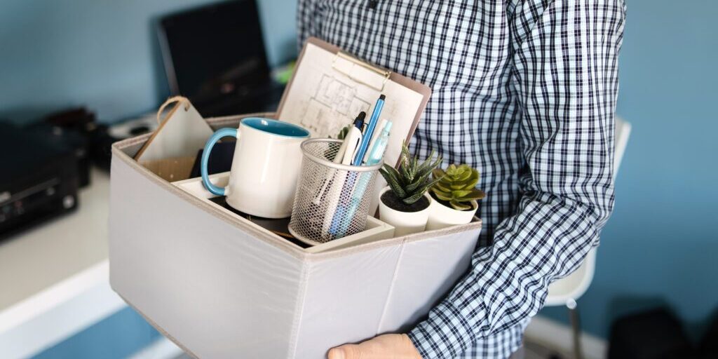 Midsection close up of unknown caucasian man holding a box with personal items stuff leaving the office after being fired from work due recession economic crisis downturn losing job company shutdown
